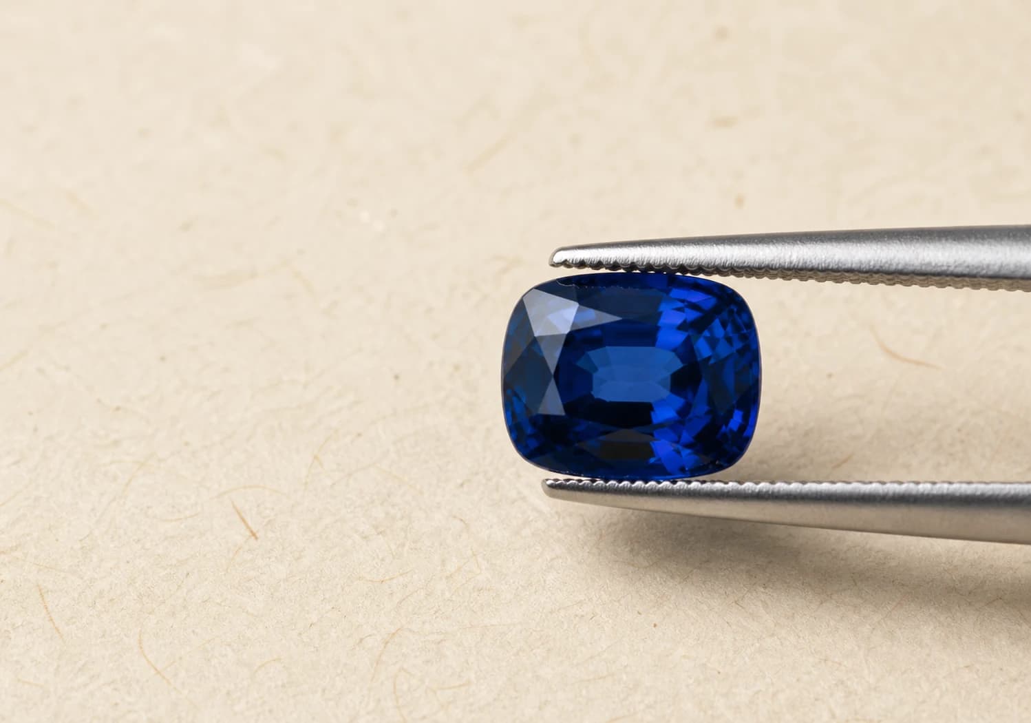 Blue gemstone held in tweezers